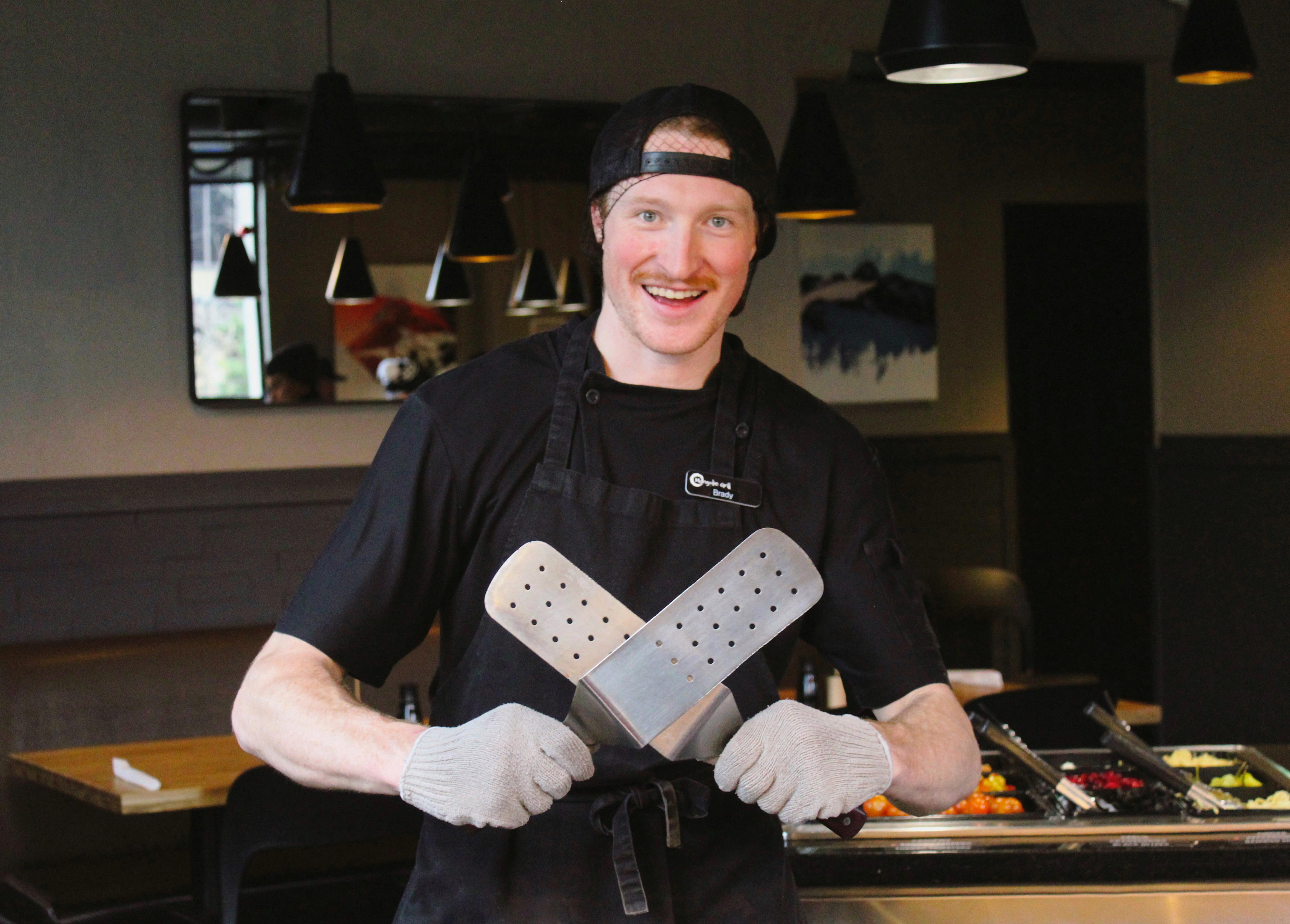 Smiling chef crossing two giant spatulas