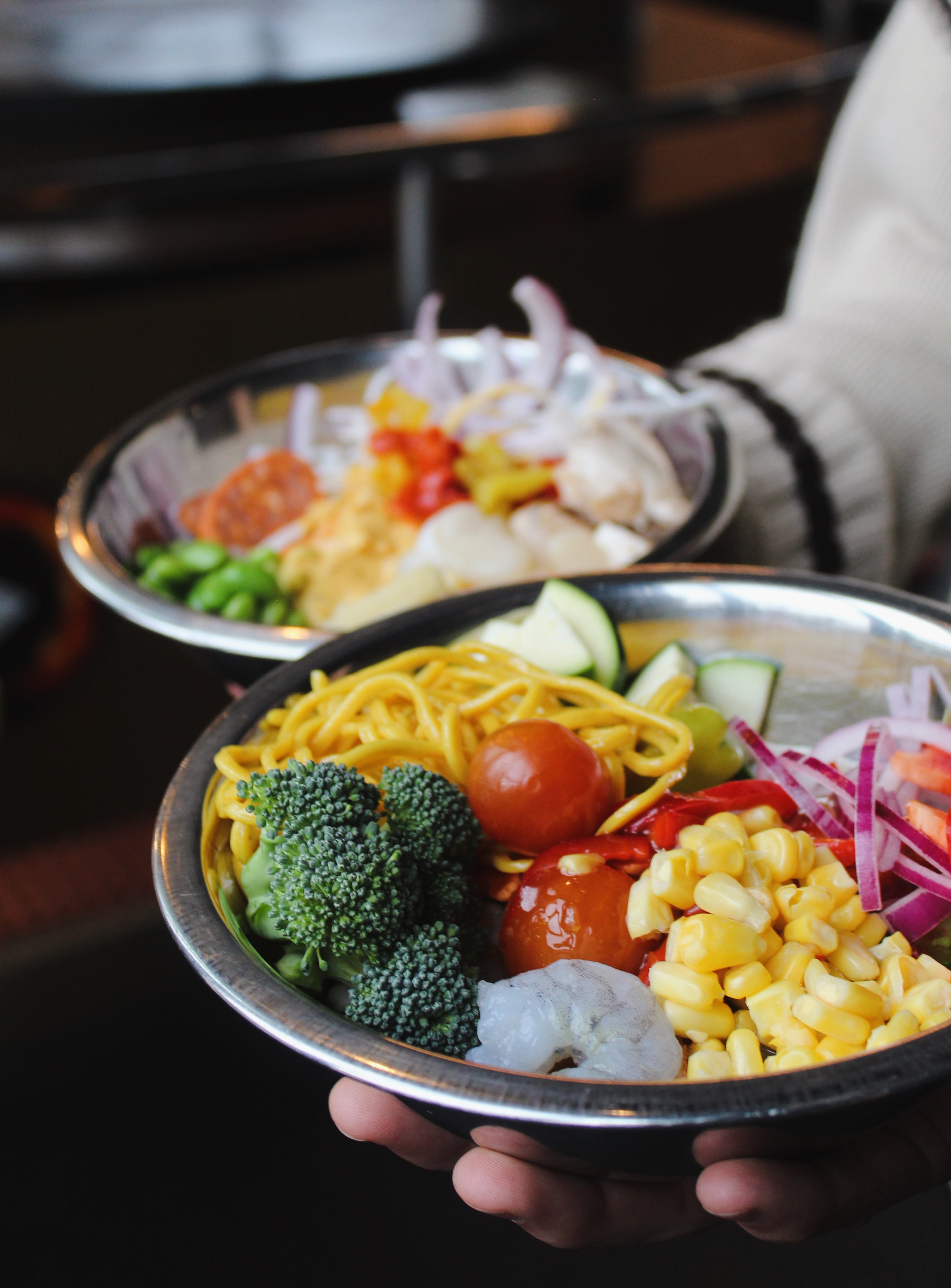 Two colorful pre-grill bowls held up at Mongolie Grill